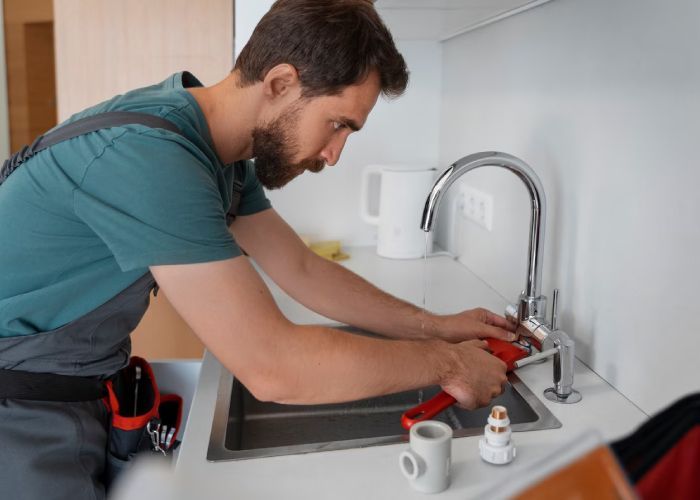 A man is fixing a faucet in a kitchen sink.