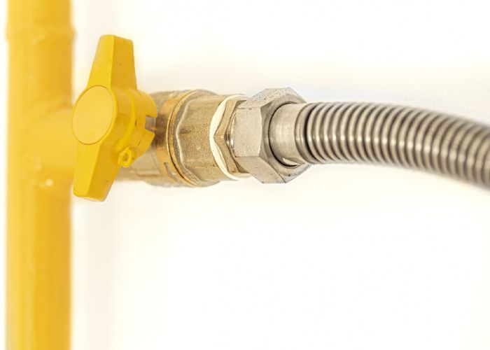 A close up of a gas valve with a hose attached to it.