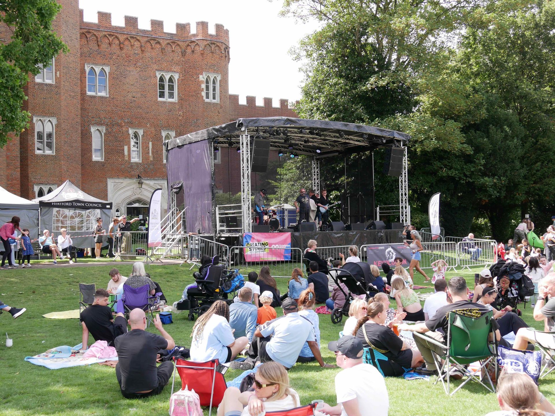 Trailer stage set up in front of Hertford Castle with a band performing on it.