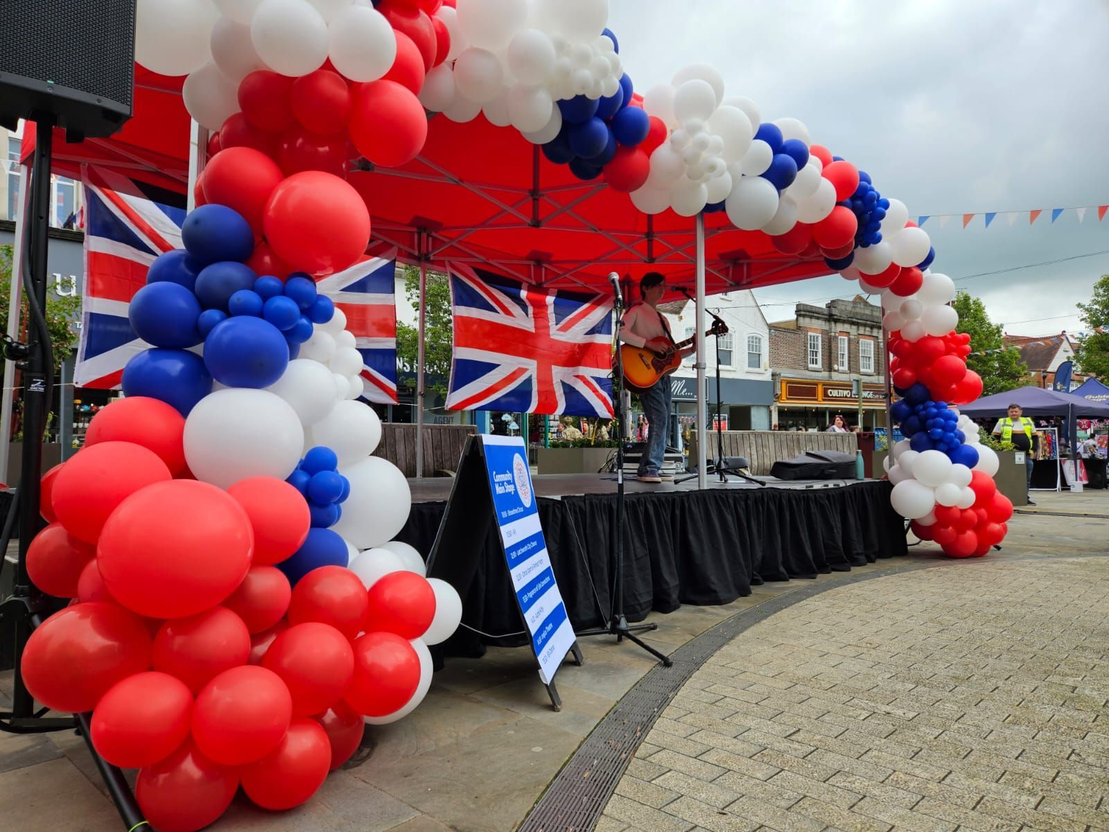 a 6m x 3m modular stage with red canopy and red, white and blue balloons around it