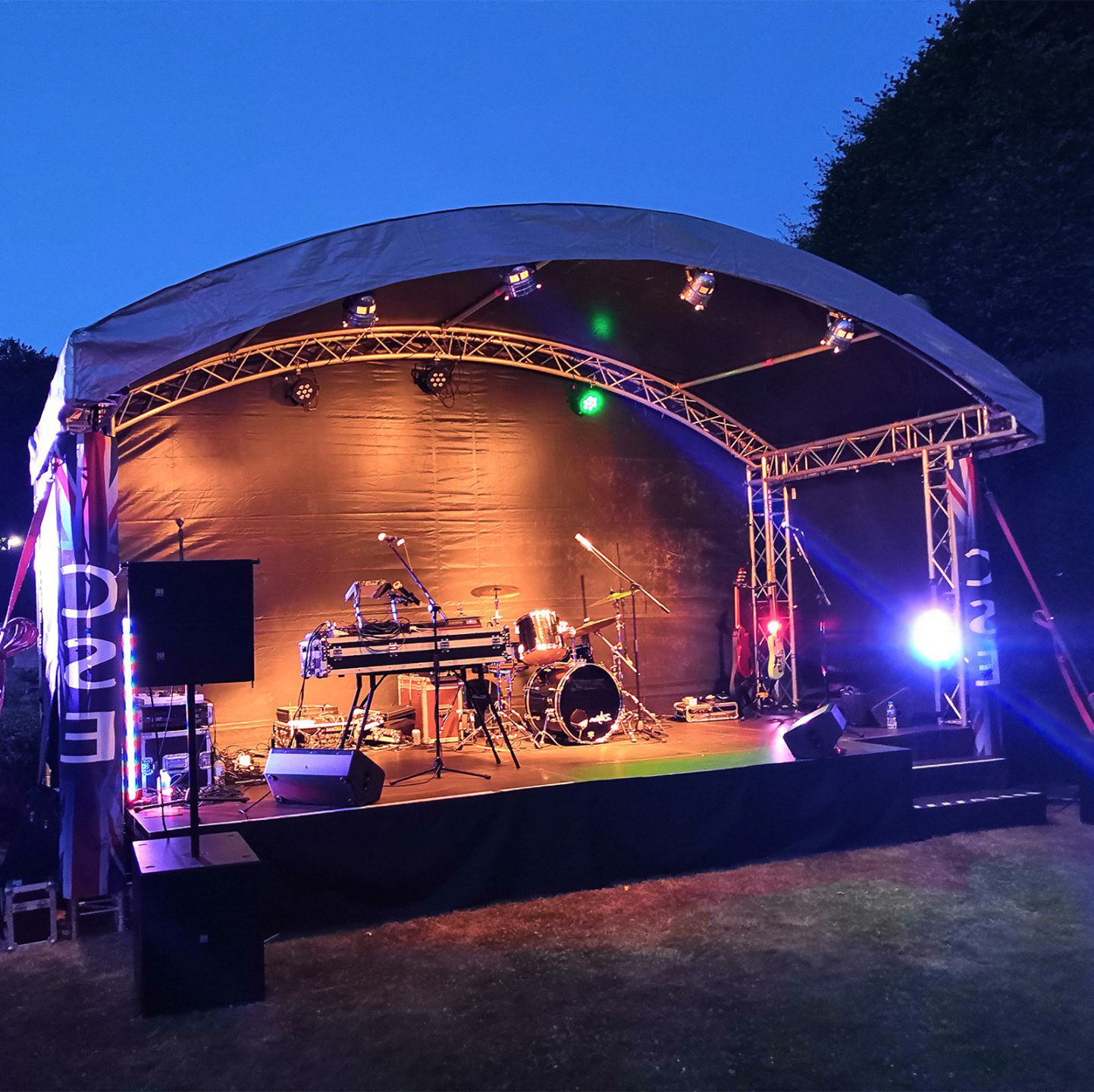 Arc stage set up on the evening with coloured lighting and PA system