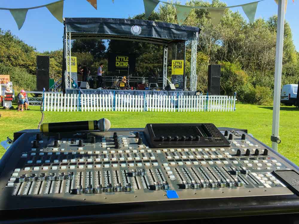 In the foreground there's a sound desk set up and in the background the trailer stage is set up for an event.