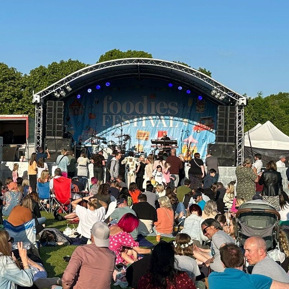 a large arc truss stage with a band playing and an audience watching on.