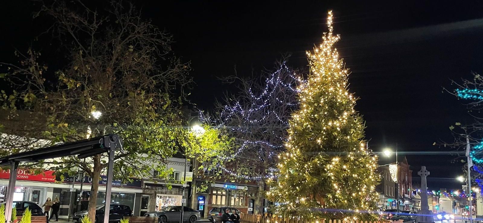 A twinkling Christmas tree in a town square at night.