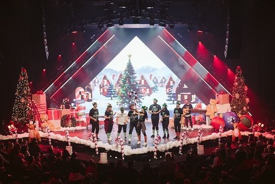 A red coloured stage decorated or Christmas with trees, presents, candy canes and fake snow