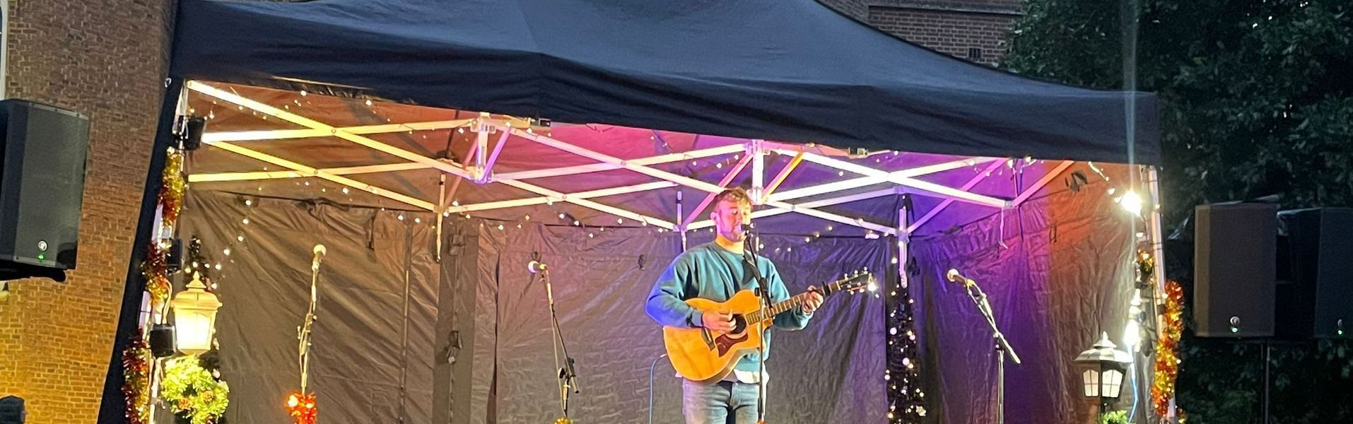 A solo performer with his guitar playing on a modular stage at christmas