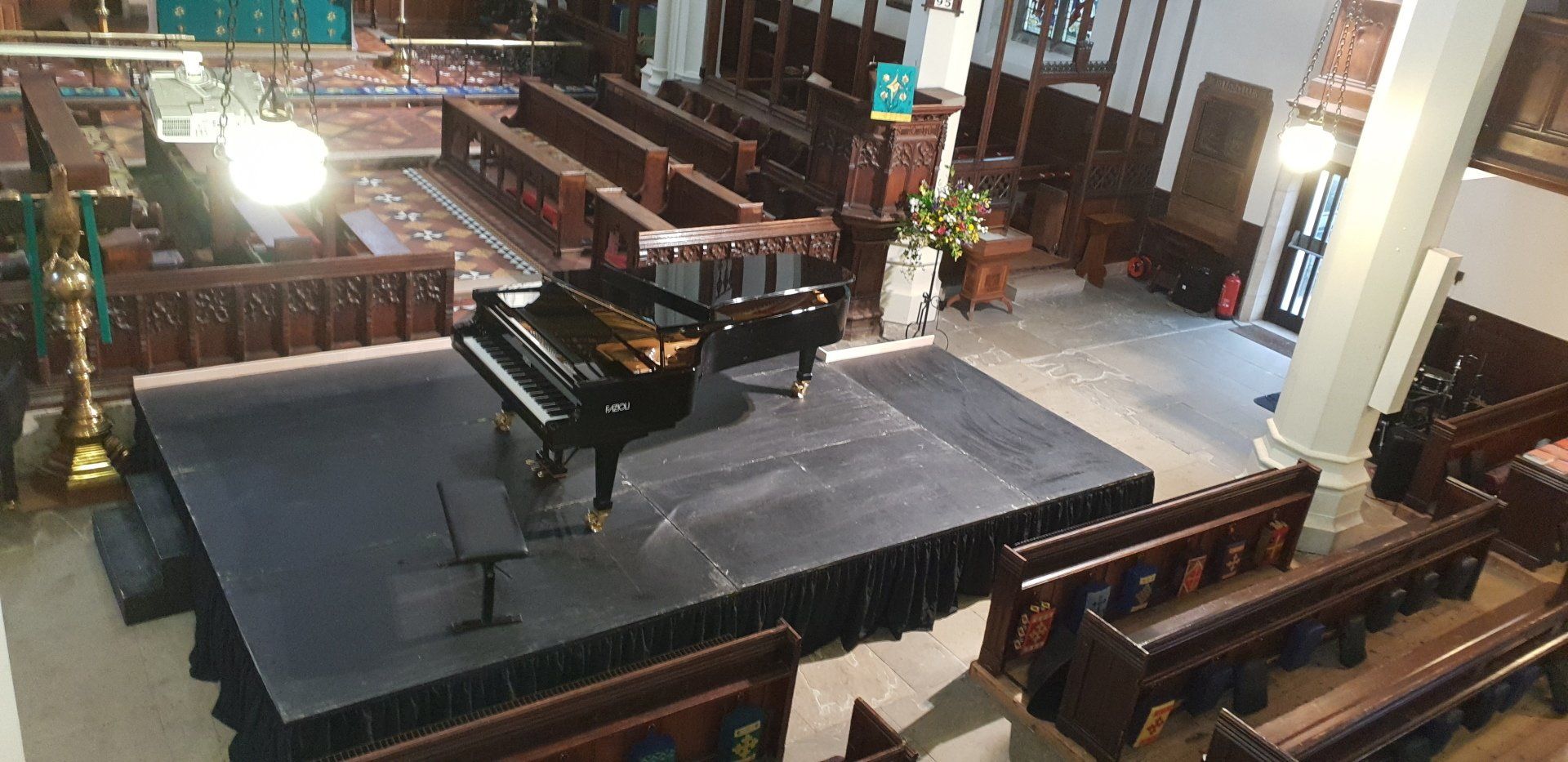 Ariel shot of an indoor modular staging set up in a church with a piano on it.