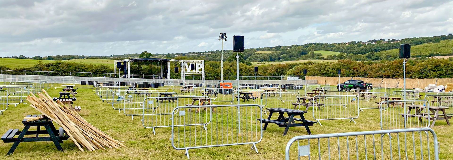 An event site set up socially distanced with a trailer stage in the background and speaker system through the site.