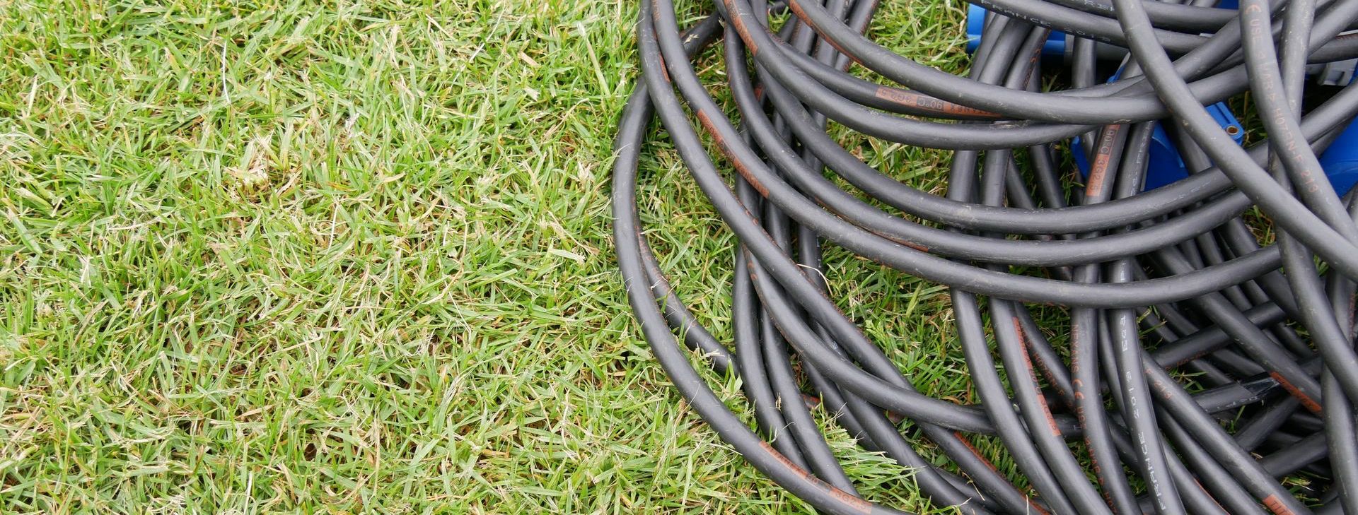 A coil of black cables on green grass