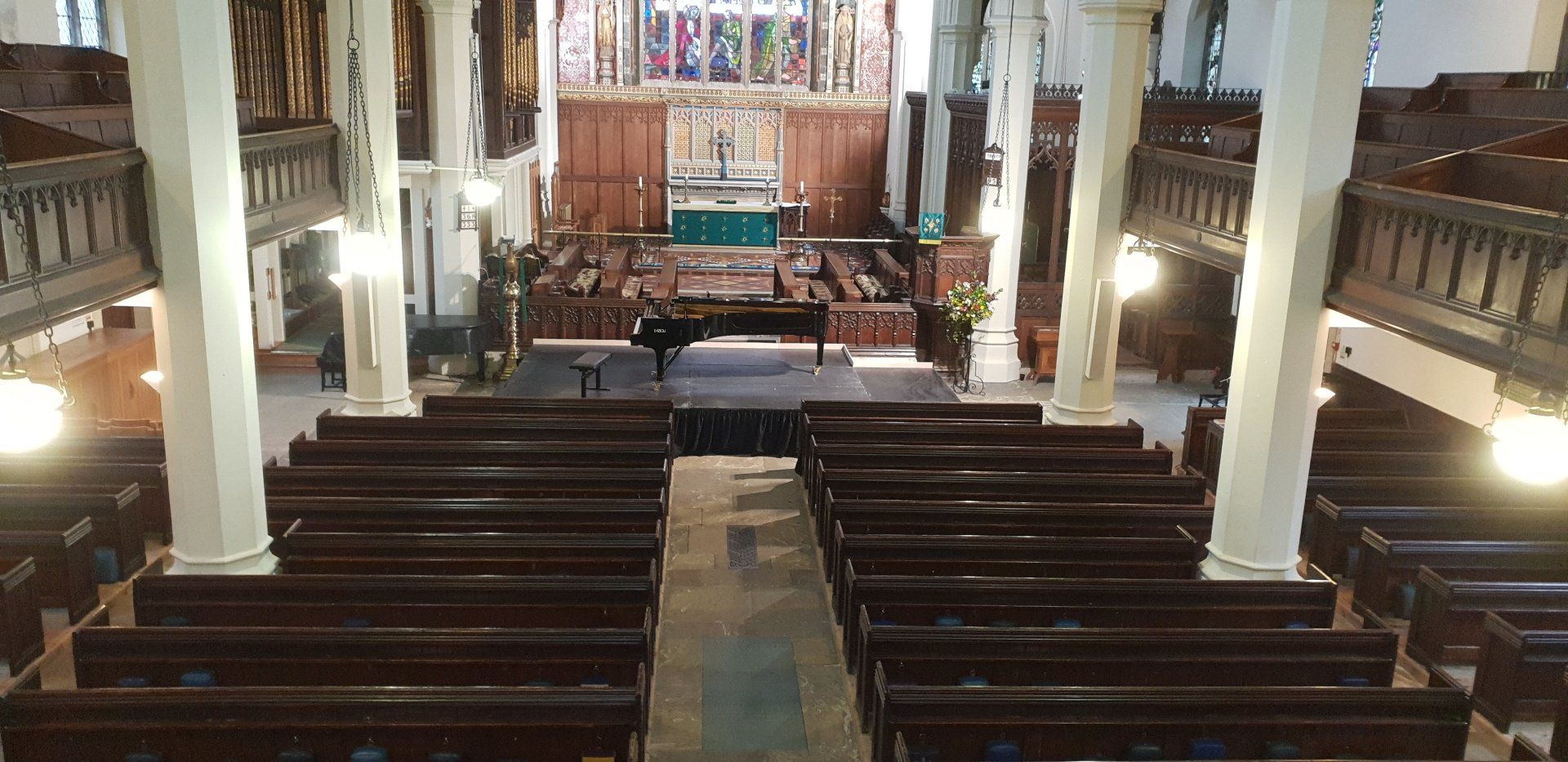Indoor modular staging set up in a church with a piano on it.