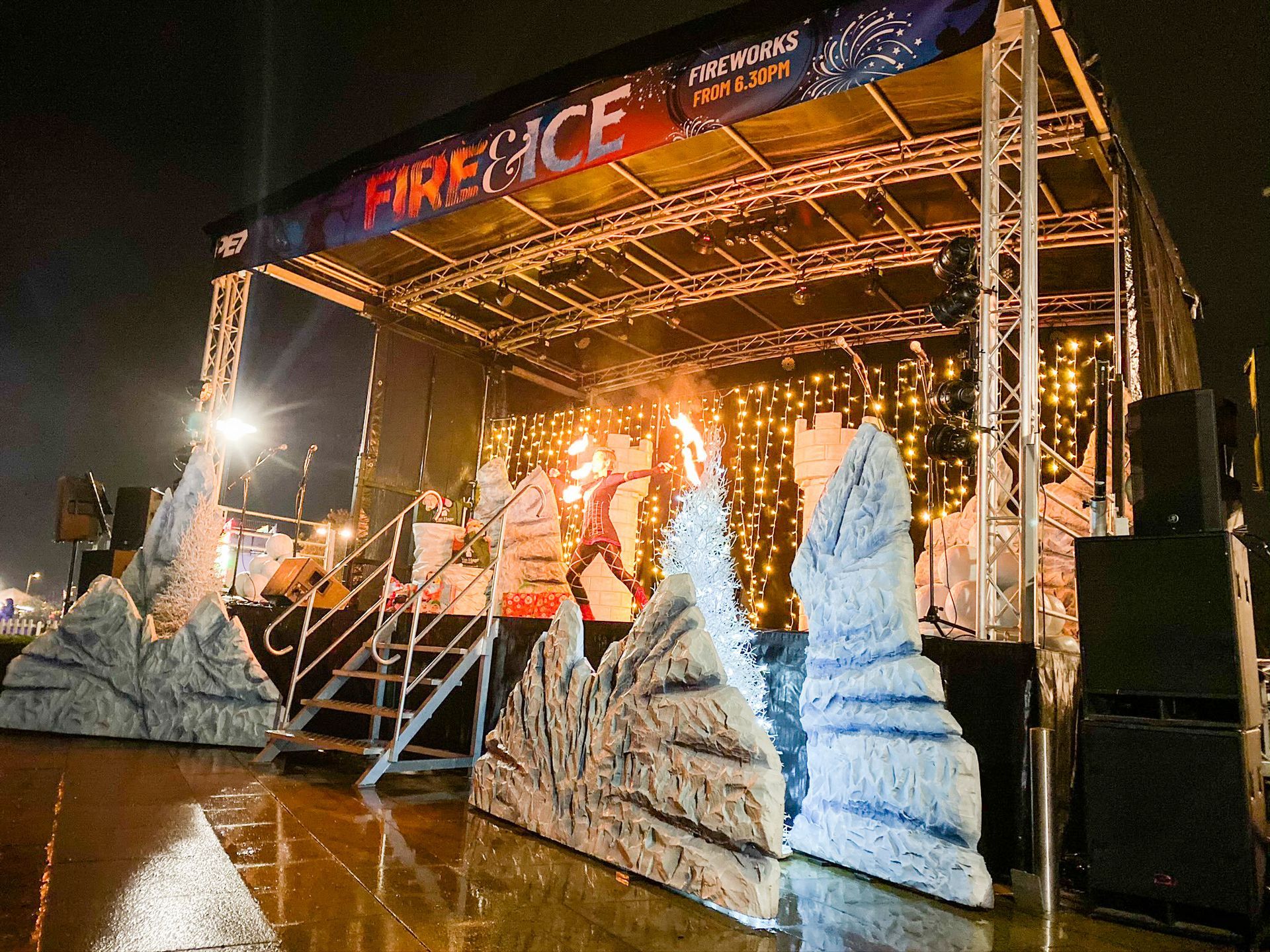 A trailer stage decorated with fake icebergs and a fire breathing performing on it.