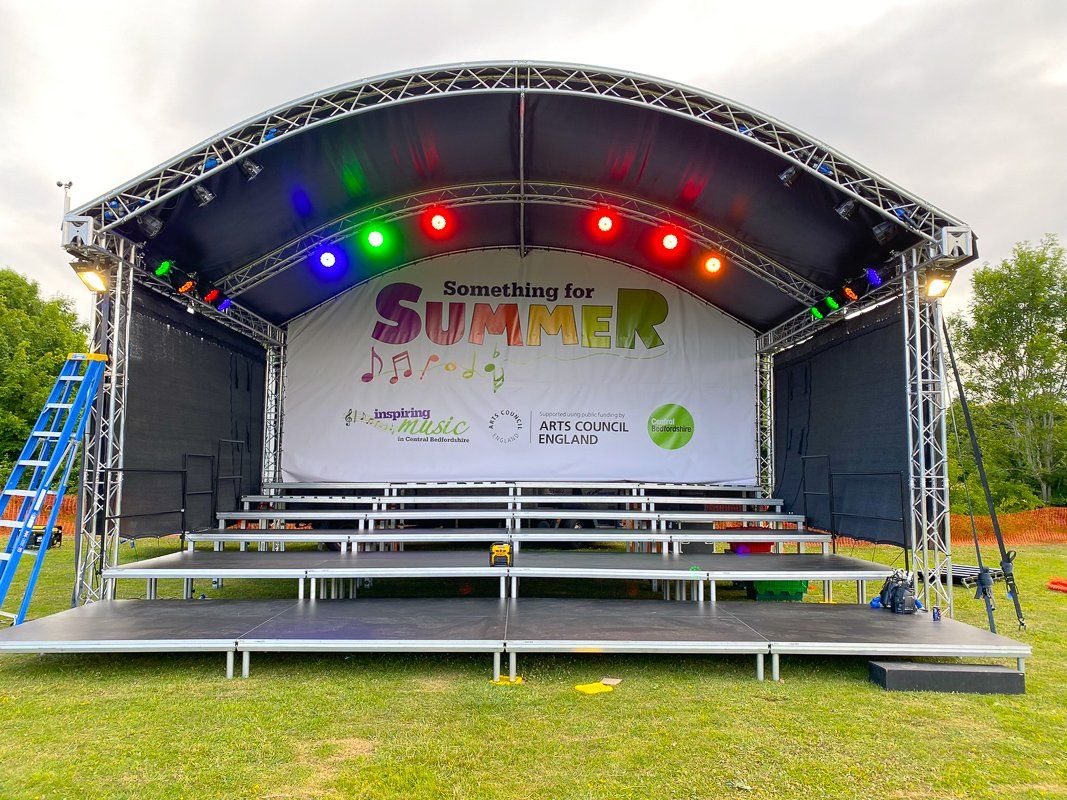 Arc roof stage set up for an outdoor event with lighting package