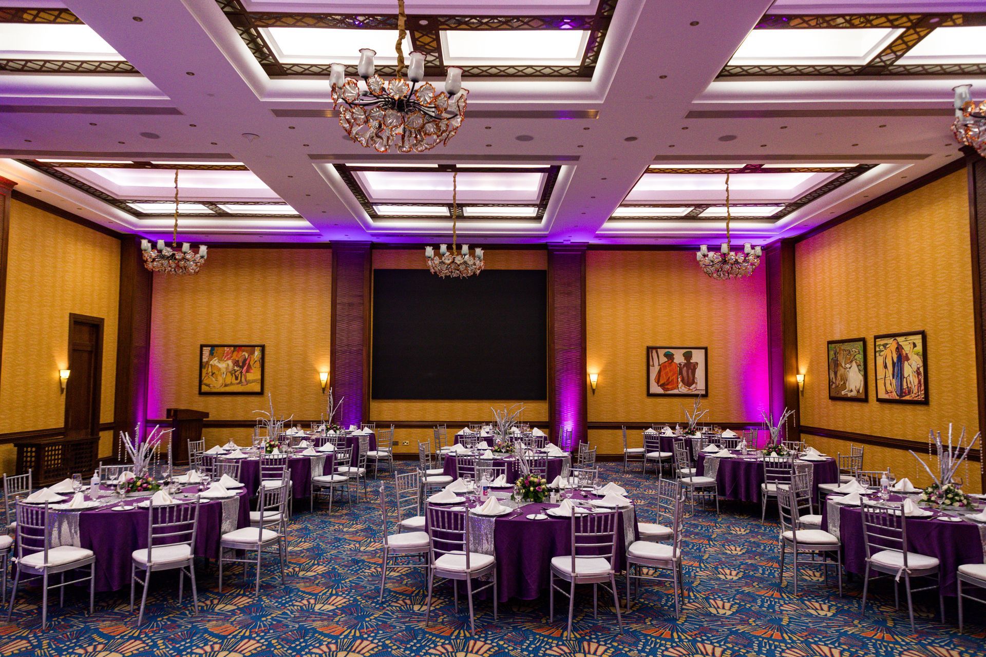 A wedding reception set up in a venue with purple uplighters