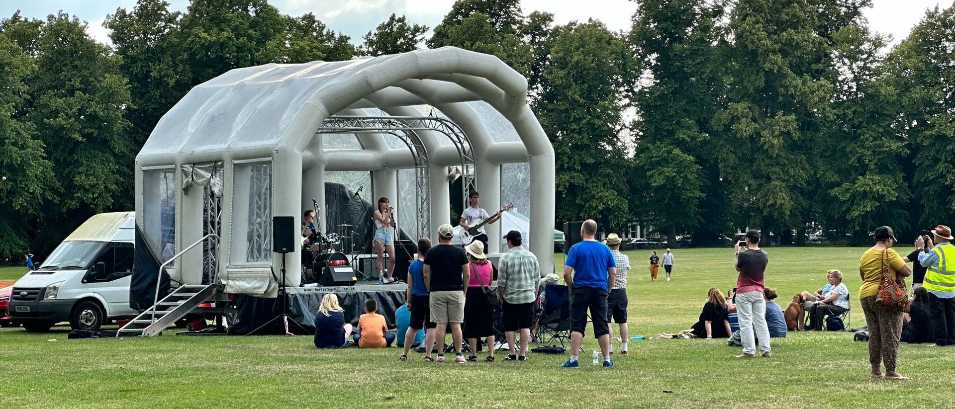 Inflatable stage at a community festival with a band performing on it and an audience watching on