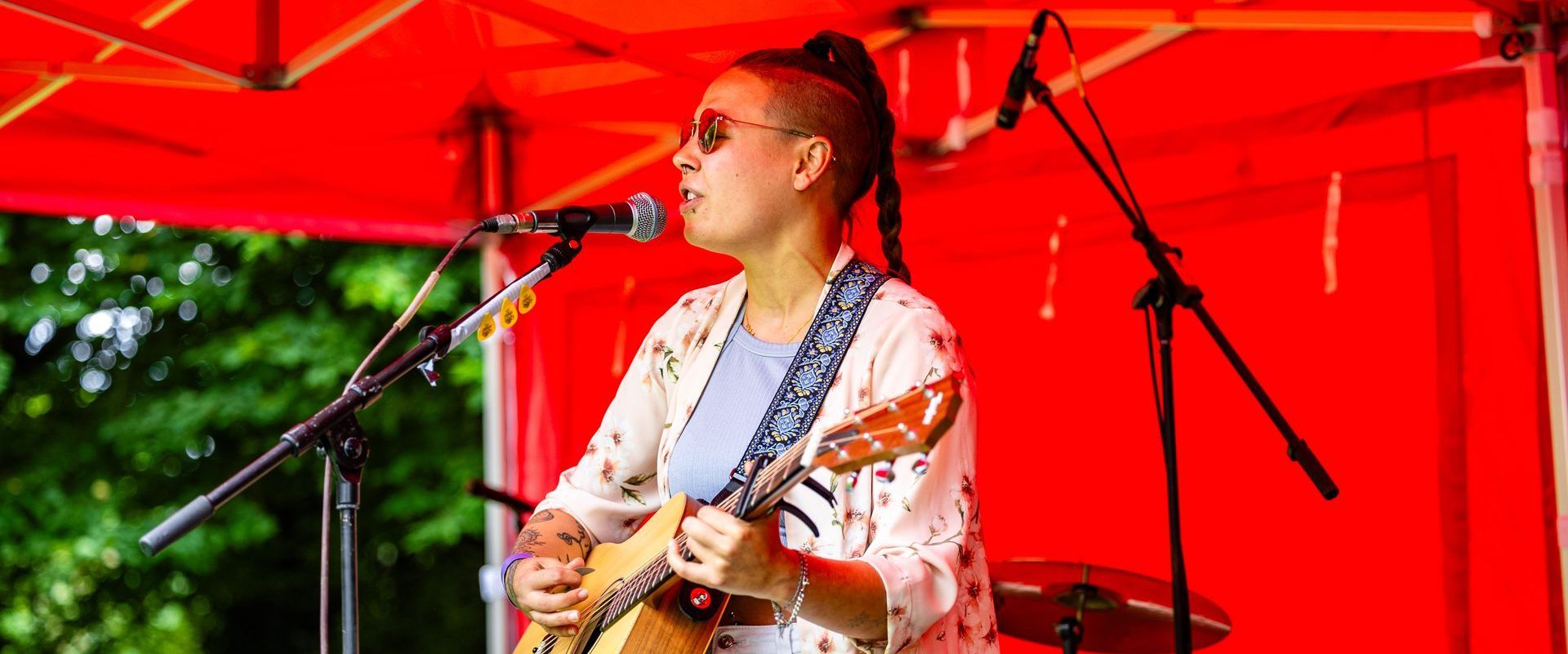 A performer playing the guitar on a red topped stage at Rock at the Castle