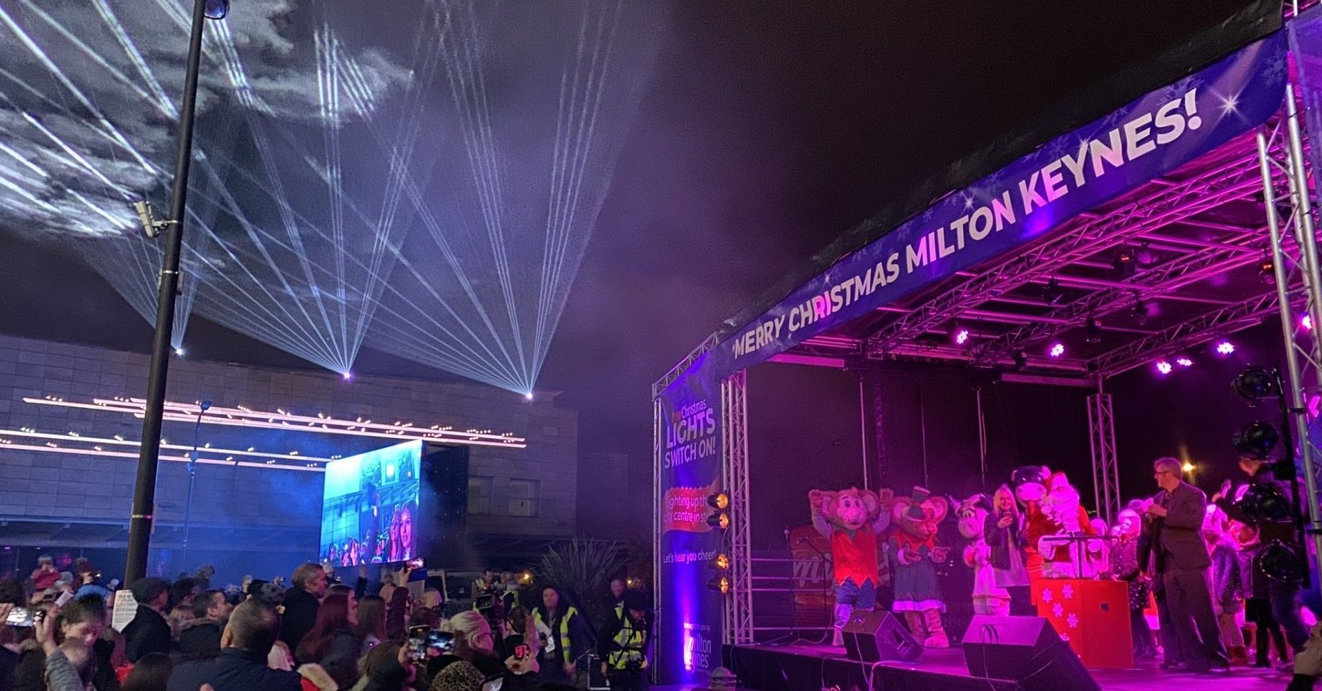 Trailer stage with Christmas banners on top and on PA wings, with an audience and lasers in the sky