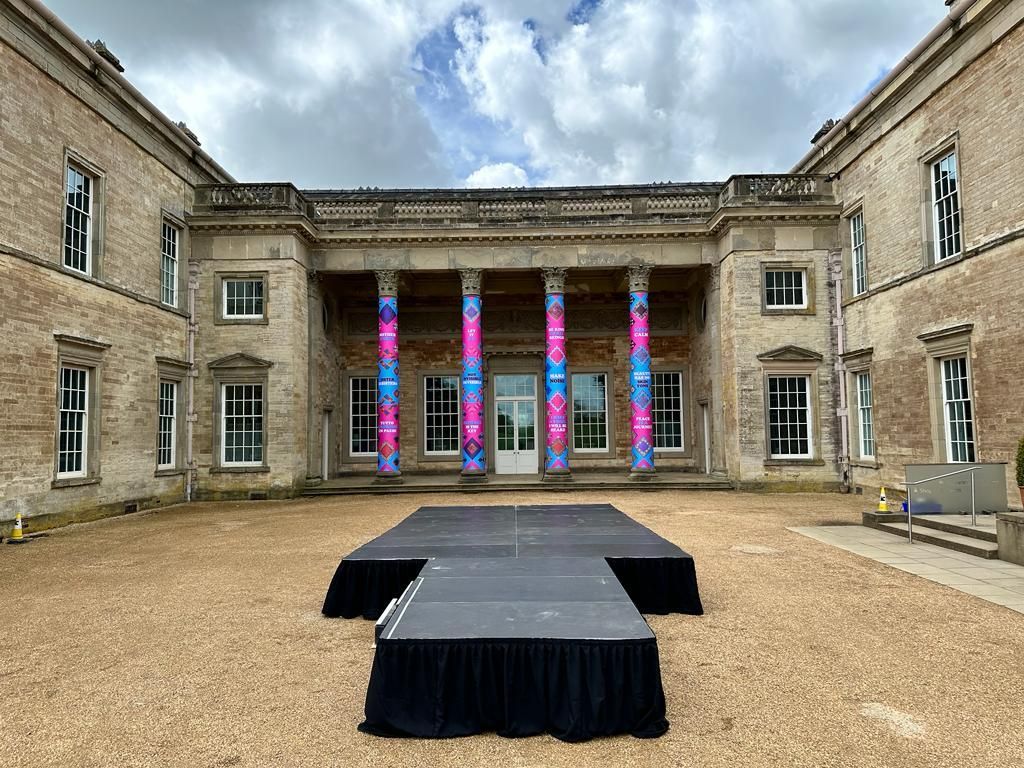a modular stage set up as a T in the middle of a gravel courtyard of a Manor House