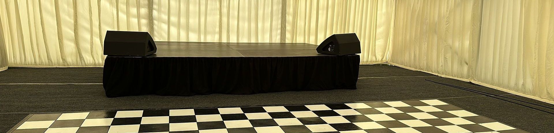 a modular stage in a marquee with a chequer board dance floor