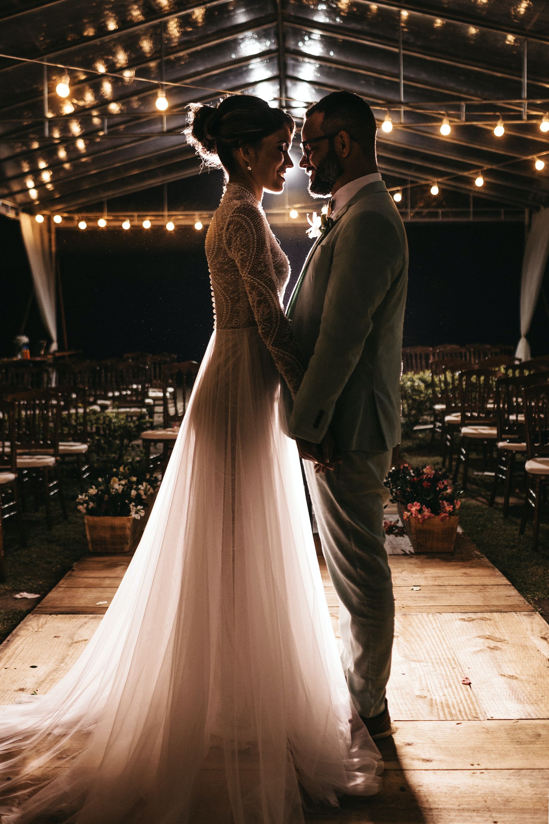 A couple standing at the altar with festoon lighting behind them