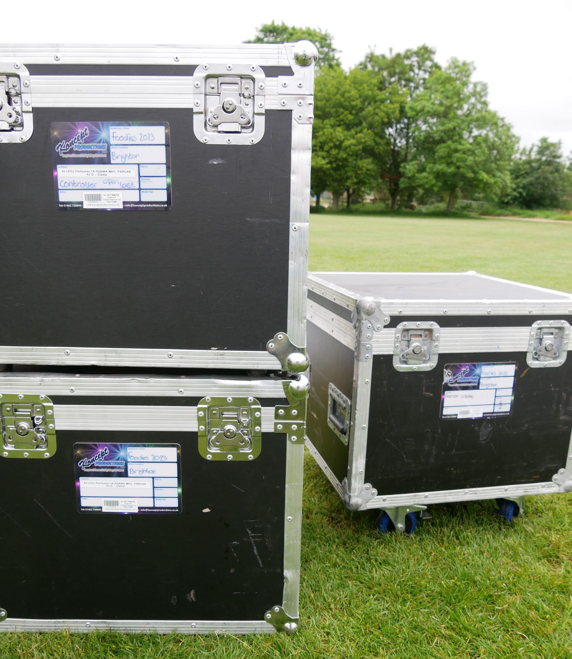 A close up of black flight cases stacked in a field.