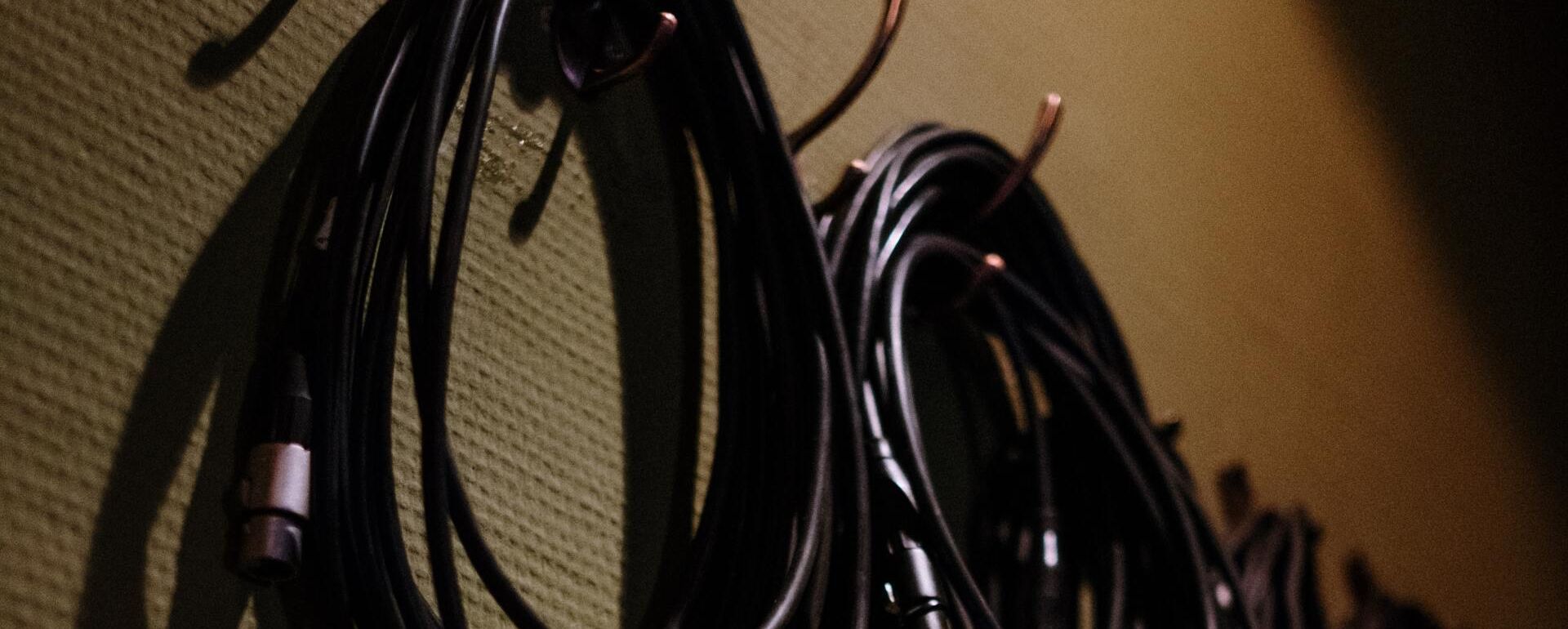 black cables hanging on hooks on a wall