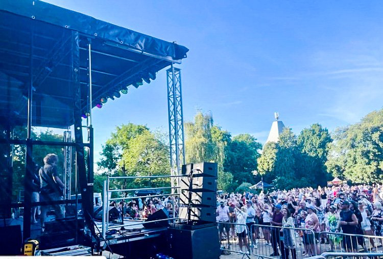 Side view of the Trailer stage in a field with a large audience and a band performing.