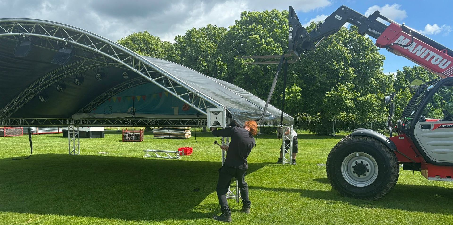 A truck setting up the roof of an arc truss stage