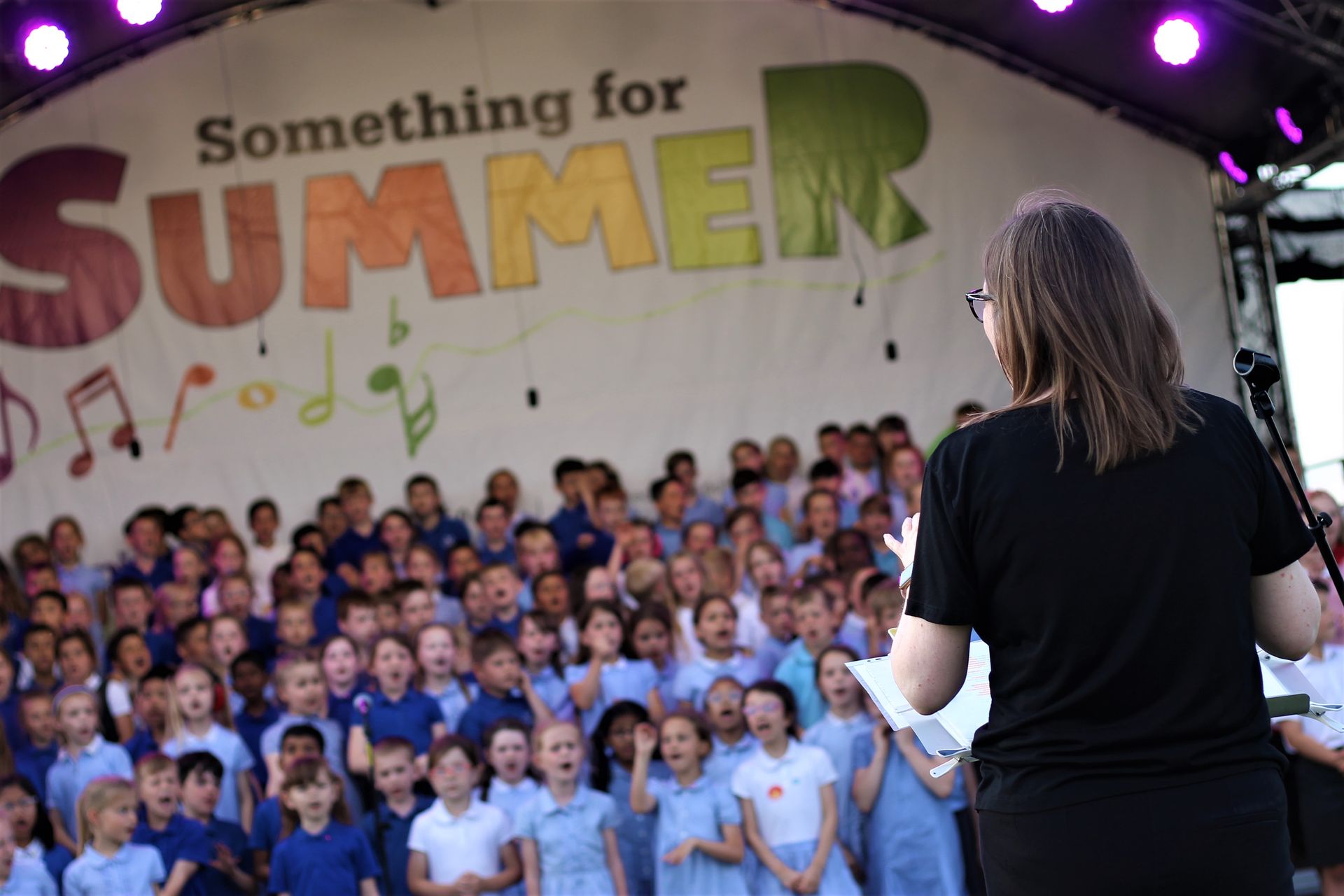 A school choir performing on an arc roofed stage