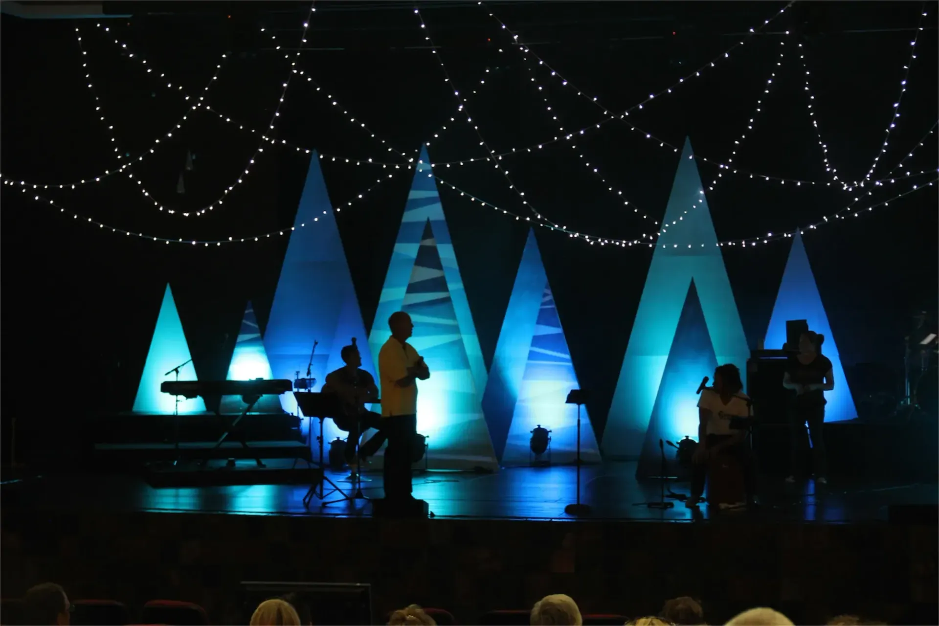 Simple Christmas Stage decorations with triangular Christmas trees light up and fairy lights draped at the top.