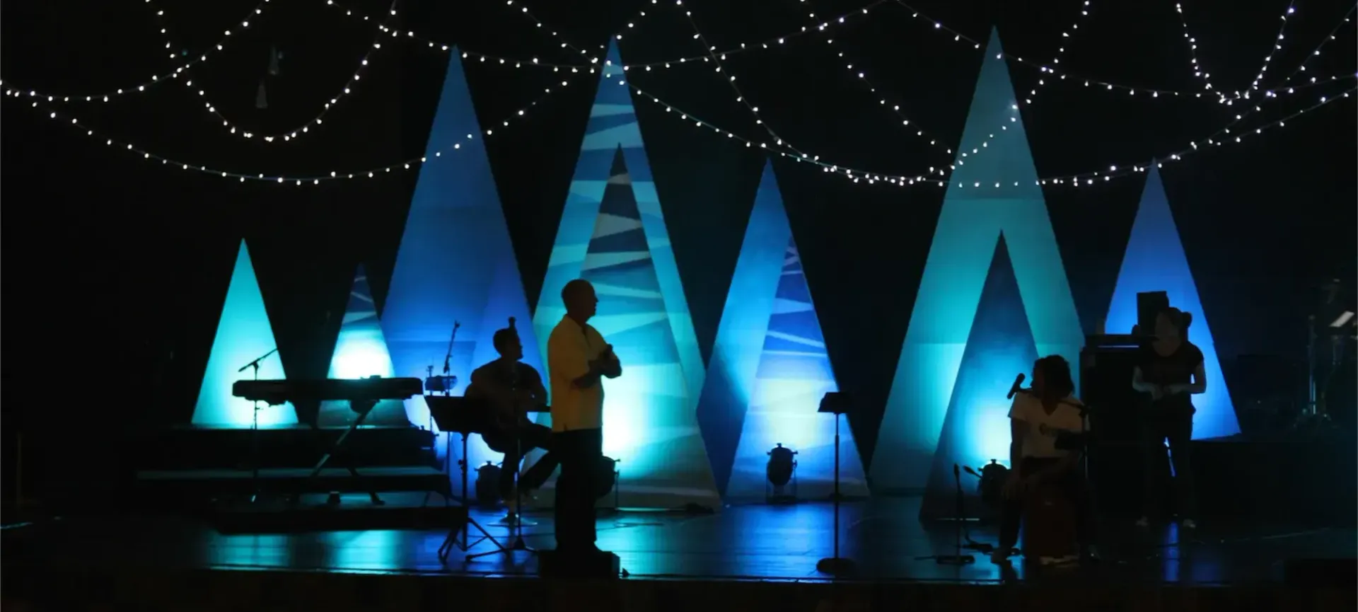  Dark stage with lit up Christmas tree props at the back