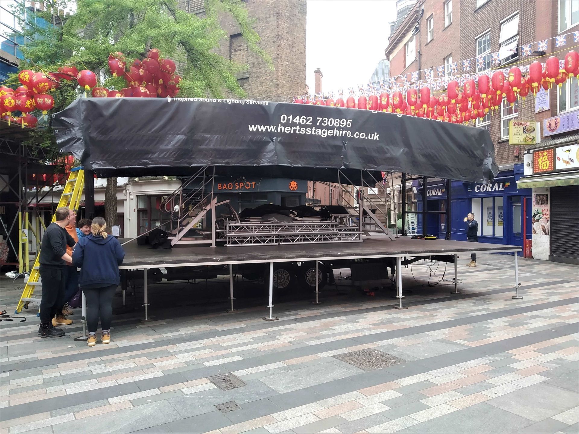 the trailer stage in process of being set up at the chinatown event - there are Chinese lanterns hanging above it