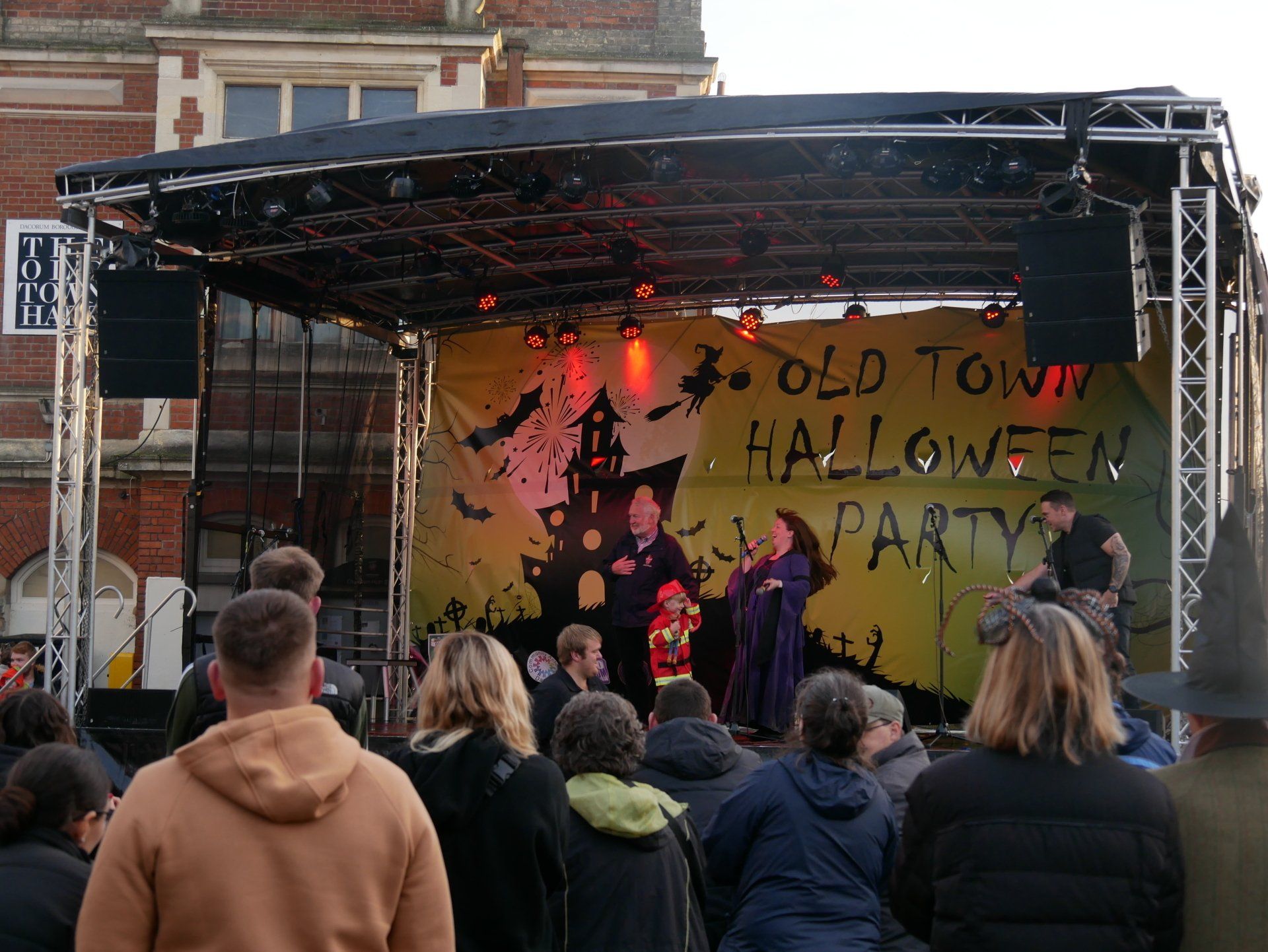 Arc Truss stage with A yellow Halloween party banner surrounded by a croud
