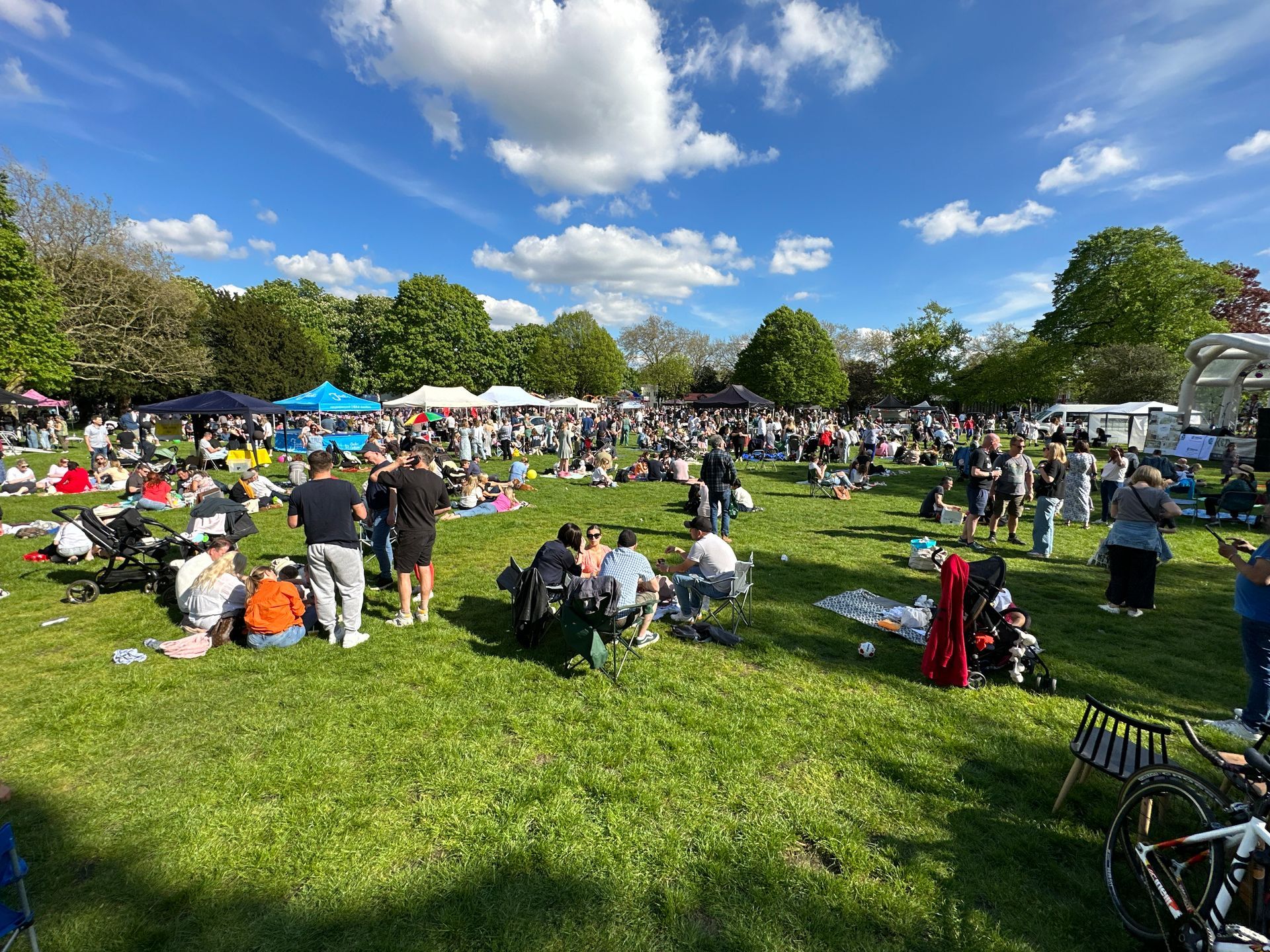 an open field at a festival with stall holders down the tree line at the back and people wandering around