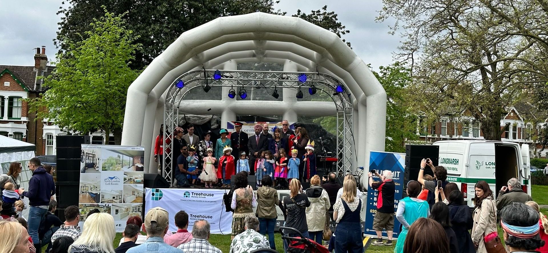 an inflatable stage with dignitaries on it and an audience watching on. 