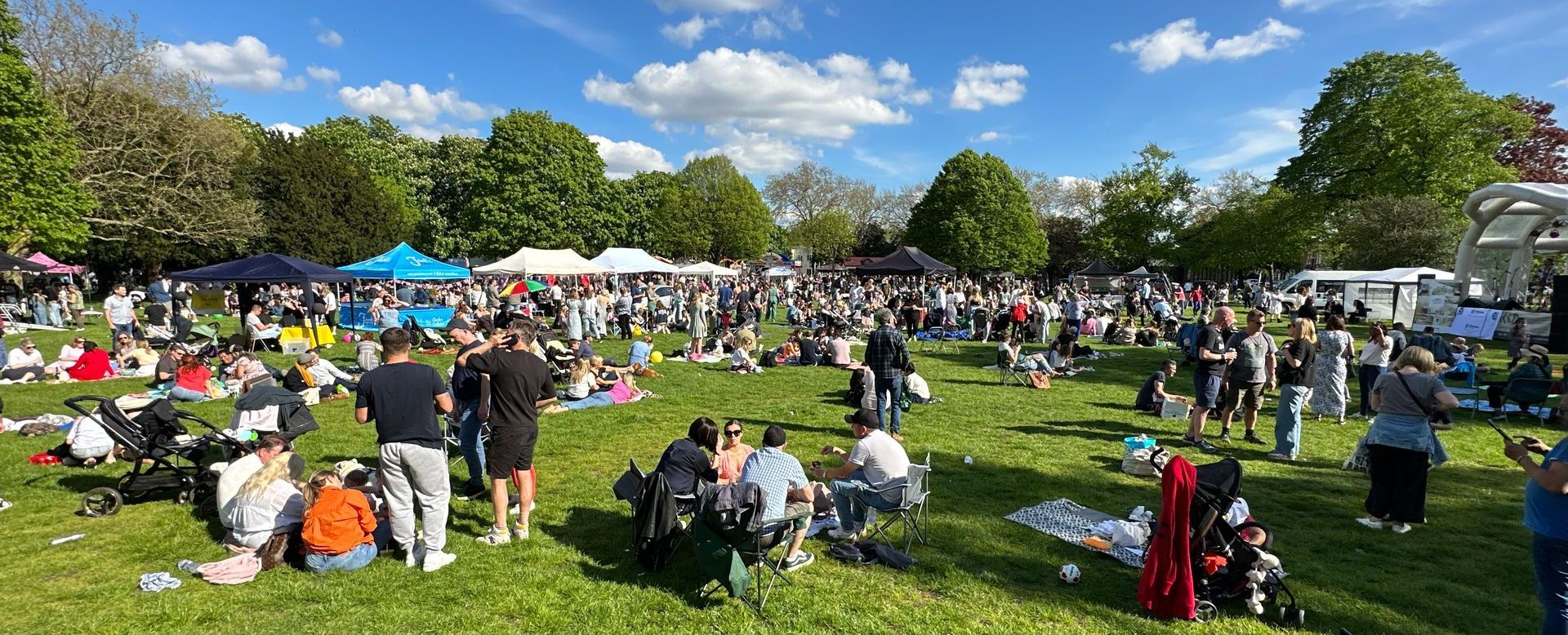 A shot of a community festival green with people picnicking on it.