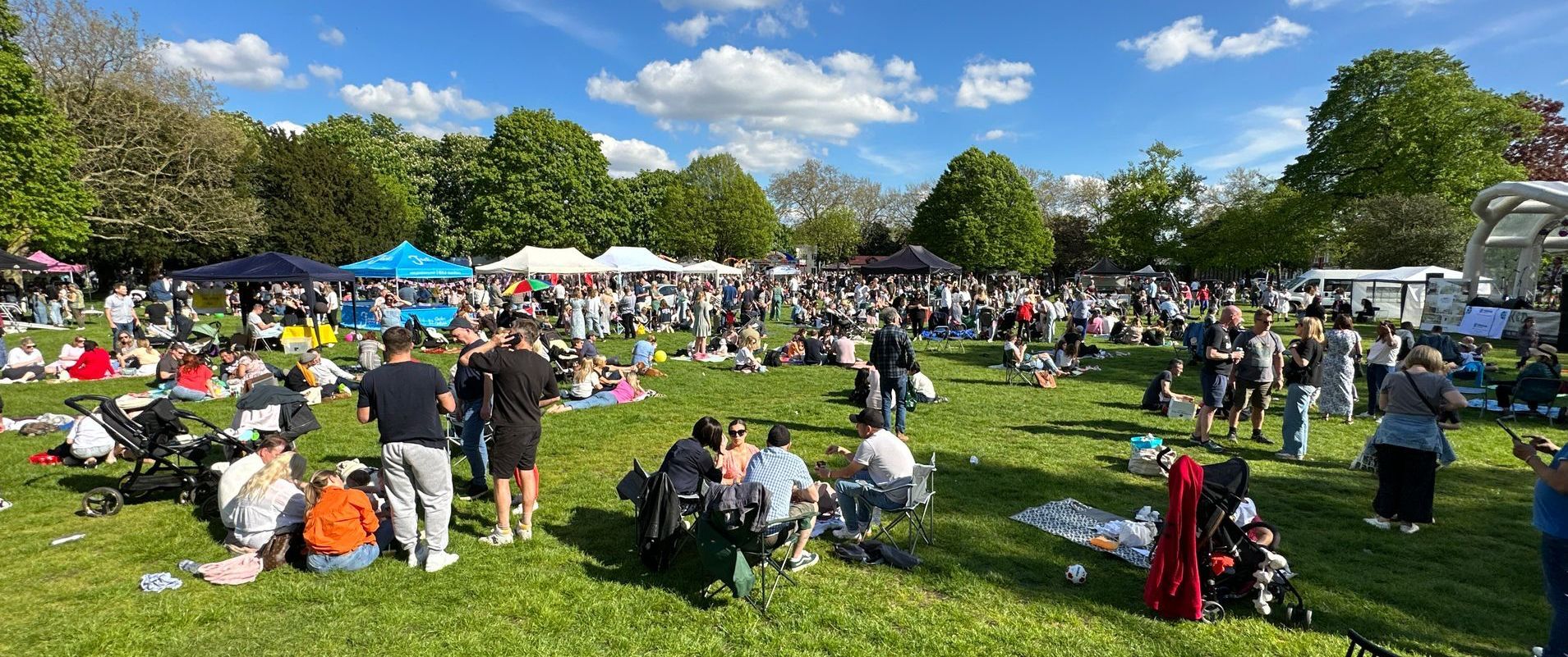 A wide shot of a festival with stalls and a crowd