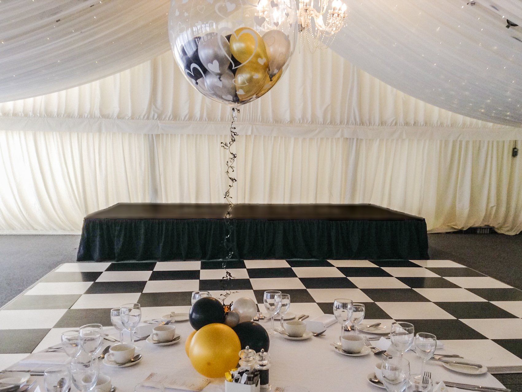 Modular stage set up inside a marquee for a wedding with a black pleated skirt.