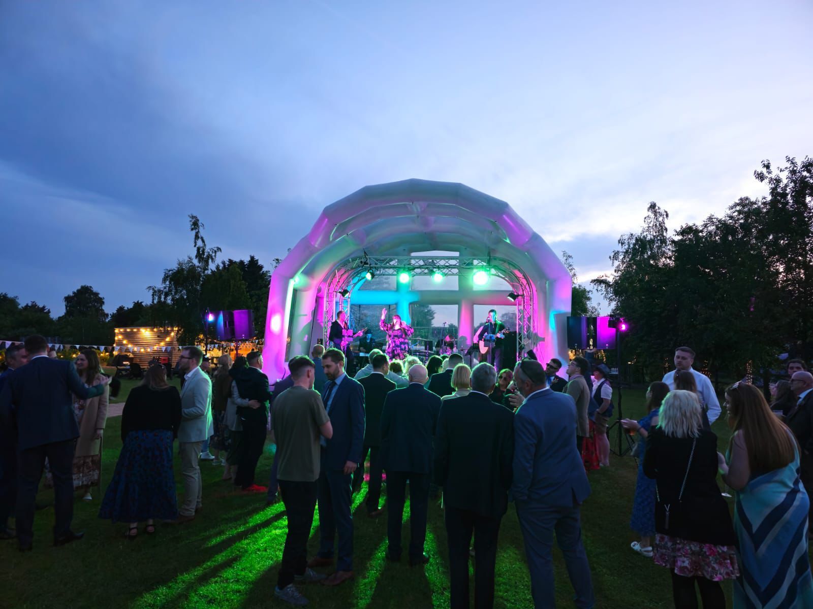 An inflatable stage at a festival wedding, with a band playing and guests watching on