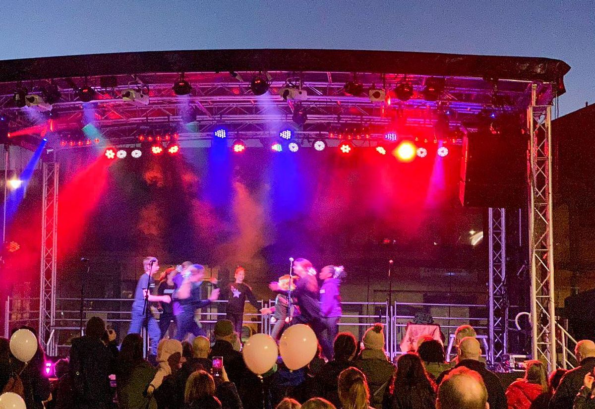 A trailer stage with blue and red lights and performers and a crowd