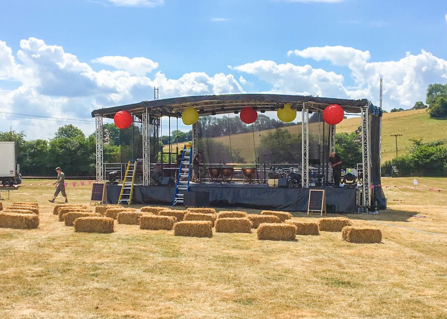 A large trailer stage set up with red and yellow decorations. Hay bails are in front of it as seating.