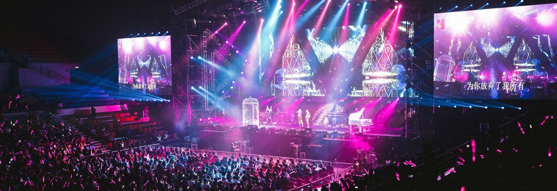 A wide shot of an arean with a stage, drenched in pink and blue colour