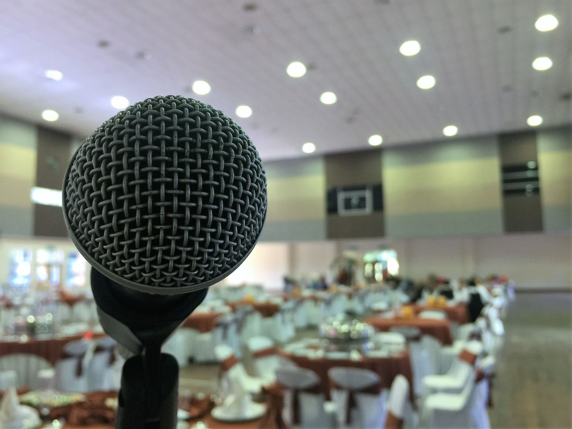Close up on a microphone with a wedding reception blurred in the background