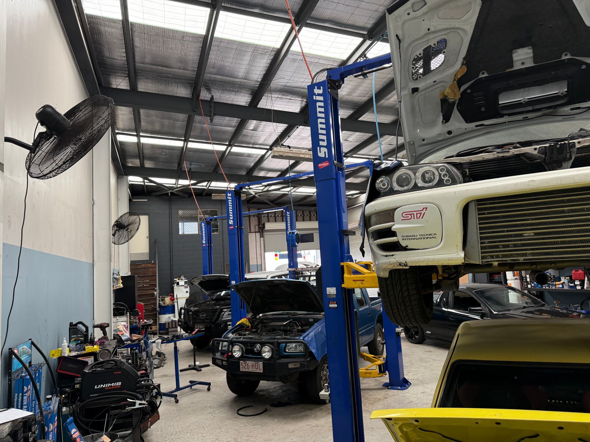 A Busy Automotive Workshop with Cars on Hydraulic Lifts, Tools, and Equipment — Mad Monkeys Mechanical in Cairns City, QLD