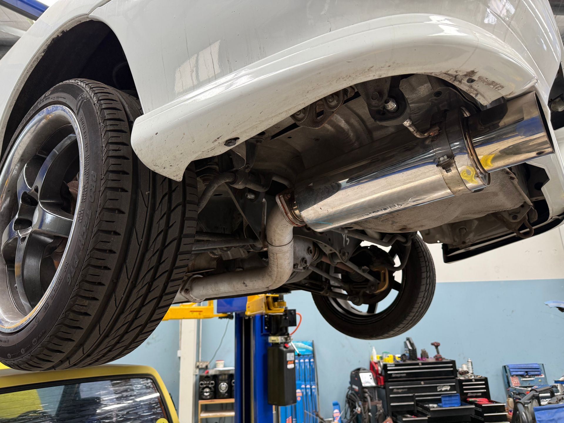 Underside of a White Vehicle Raised on a Lift in an Auto Repair Shop — Mad Monkeys Mechanical in Cairns City, QLD