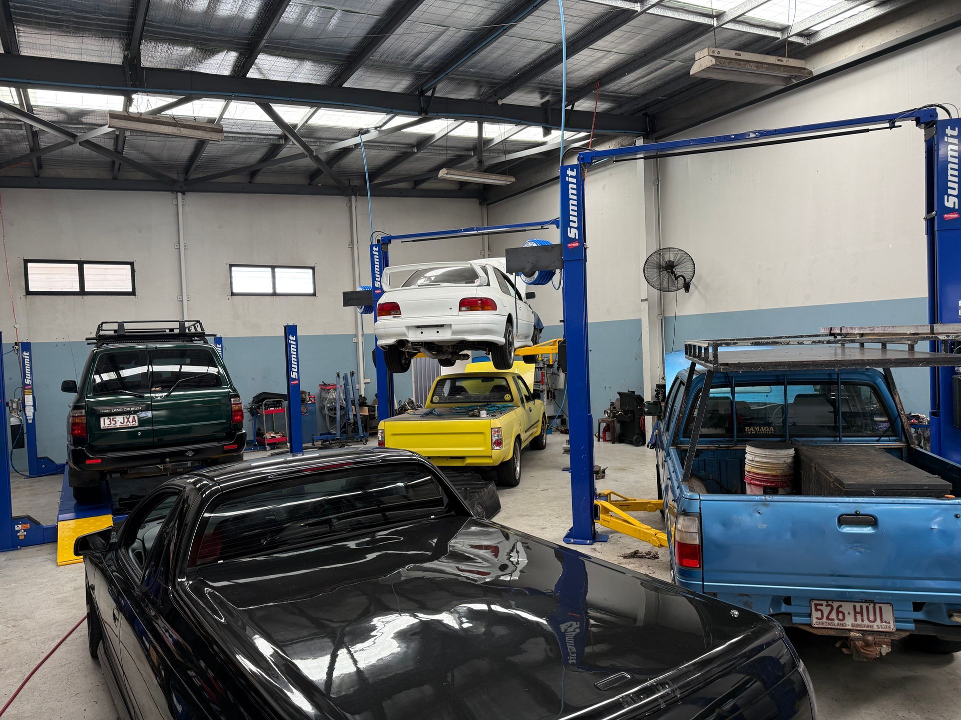 Automotive Workshop with Several Vehicles, Including a Hoisted White Car — Mad Monkeys Mechanical in Cairns City, QLD