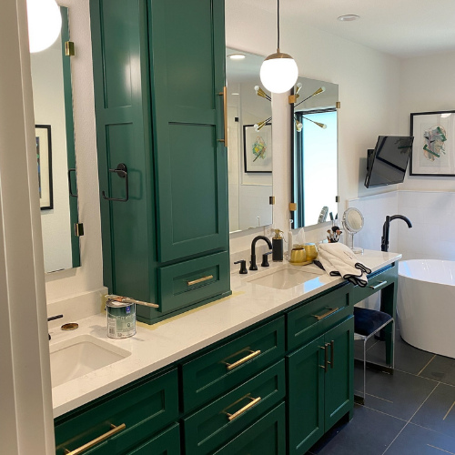 A bathroom with green cabinets , a sink , a mirror and a tub.
