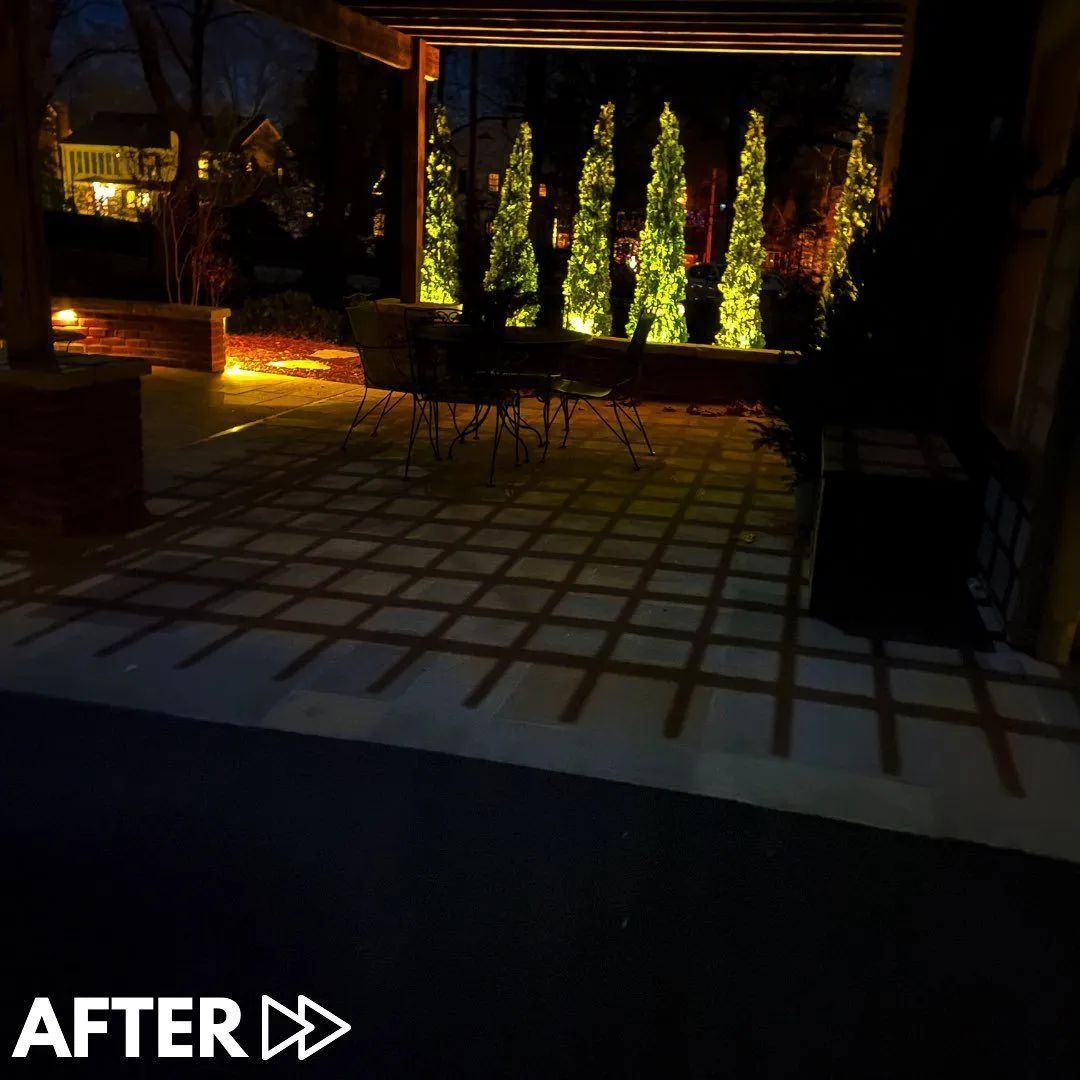 Backyard patio with pergola, brick fire pit, and stone seating area next to a house.