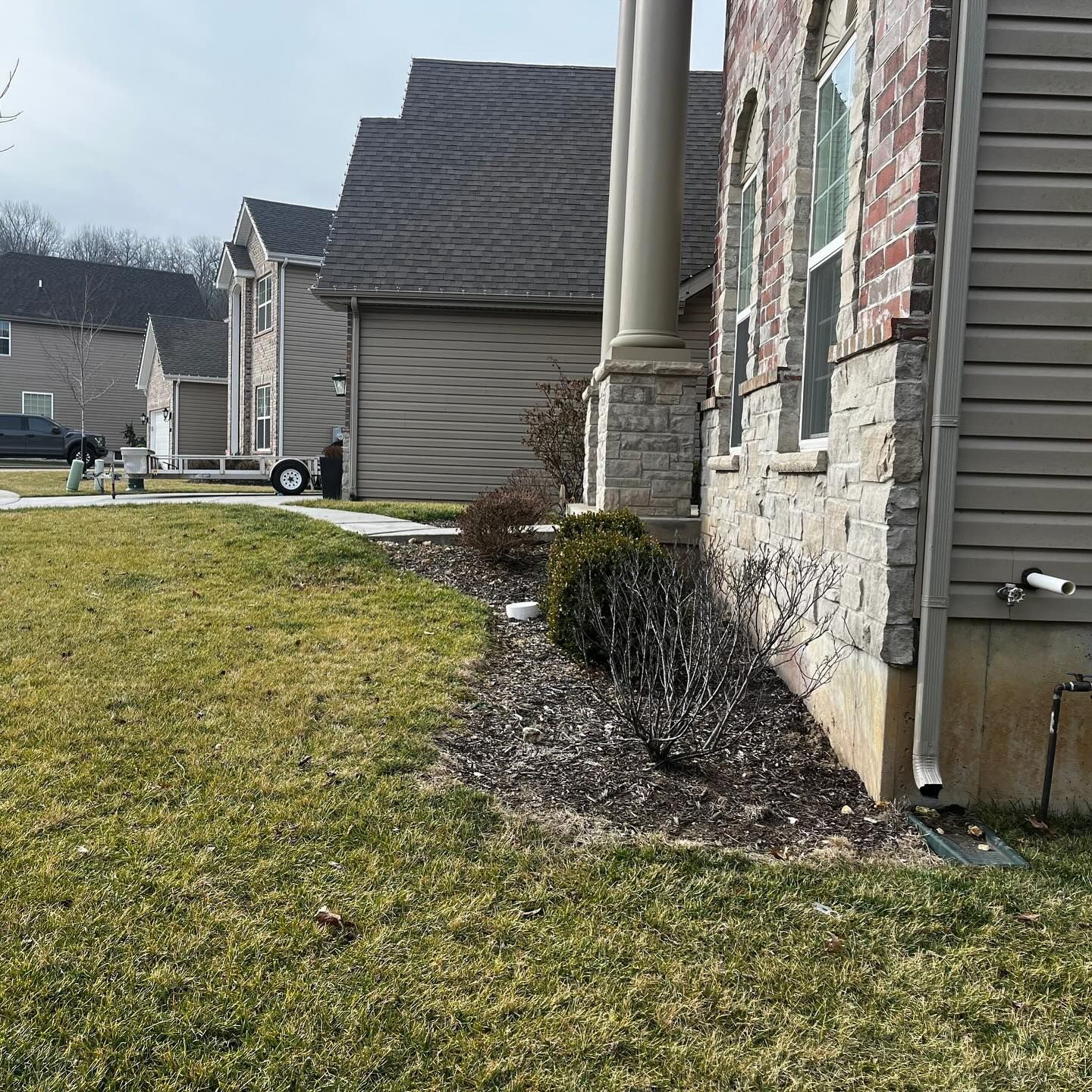 A suburban house with a brick and stone facade, a green lawn, and a driveway.