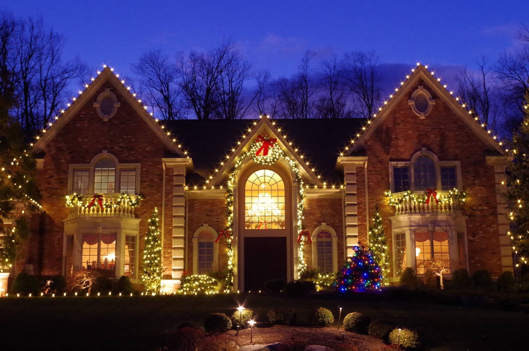 a large brick house decorated with christmas lights and a christmas tree