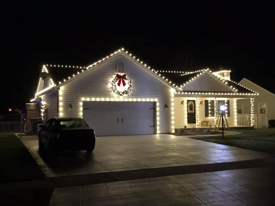 a house is decorated with christmas lights and a car is parked in front of it .